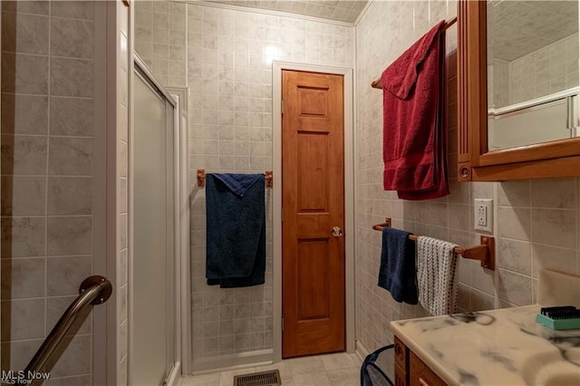 bathroom with vanity, a shower with door, and tile walls