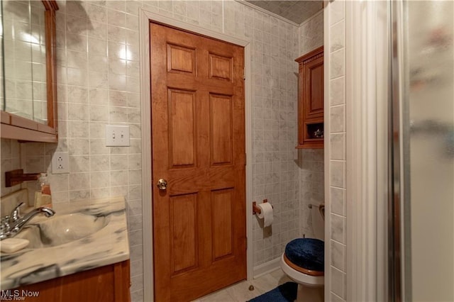 bathroom featuring tile patterned floors, vanity, a shower with shower door, and tile walls