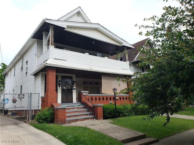 view of front facade featuring a balcony and a front yard