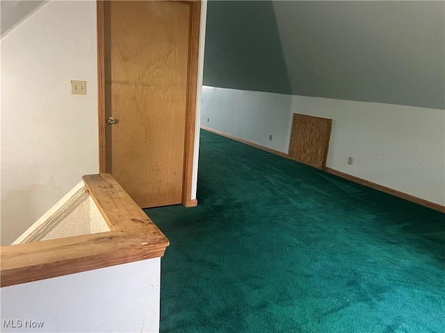 additional living space featuring dark colored carpet and vaulted ceiling