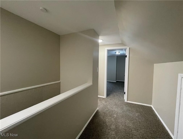 hall with vaulted ceiling and dark carpet