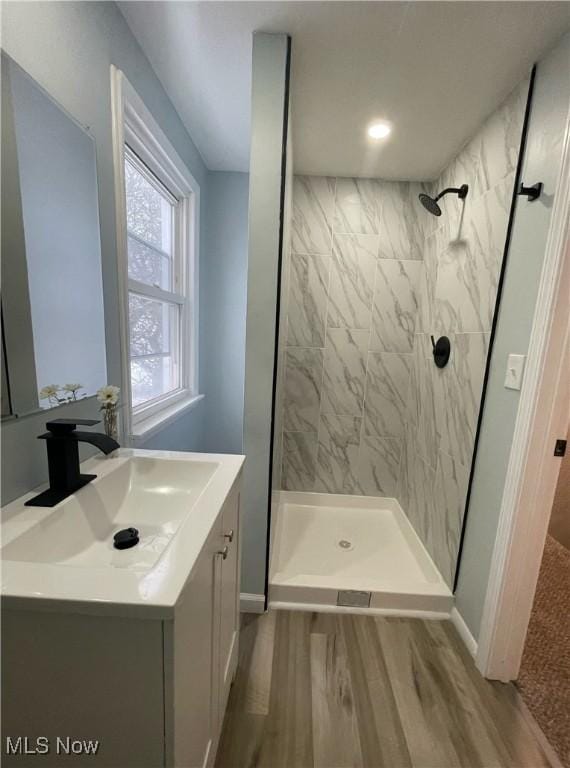 bathroom with tiled shower, wood-type flooring, and vanity