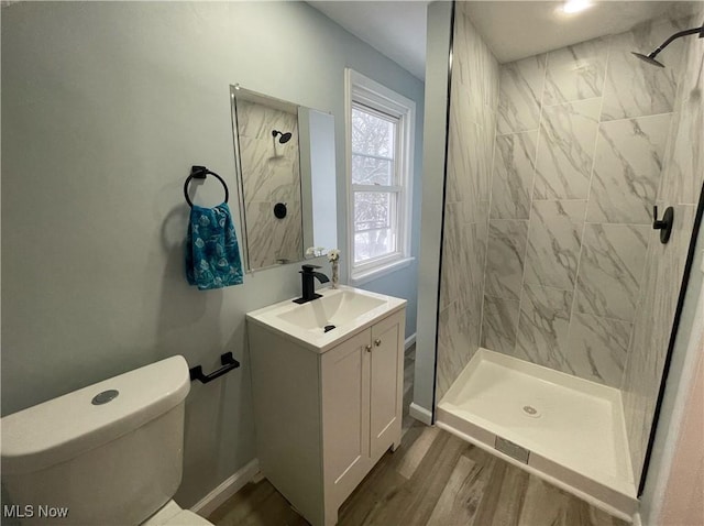 bathroom featuring hardwood / wood-style flooring, vanity, toilet, and tiled shower