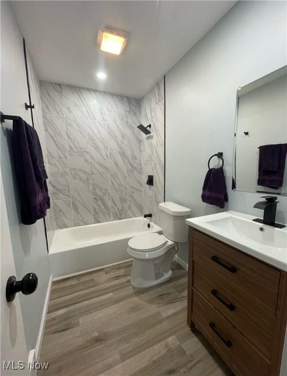 full bathroom featuring hardwood / wood-style floors, vanity, toilet, and tiled shower / bath