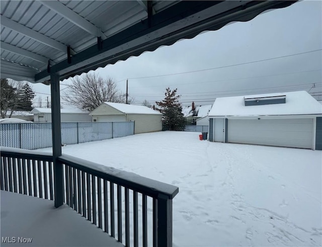 yard layered in snow featuring an outbuilding and a garage