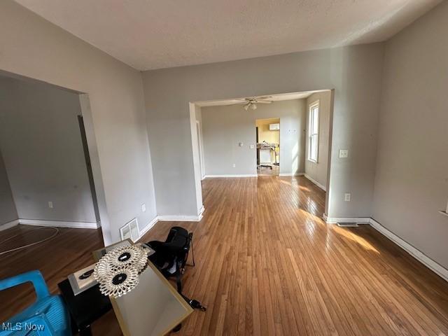 unfurnished room featuring baseboards, wood finished floors, and a ceiling fan