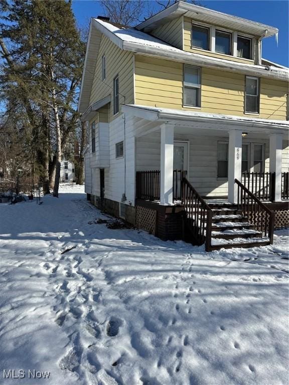 snow covered house featuring a porch