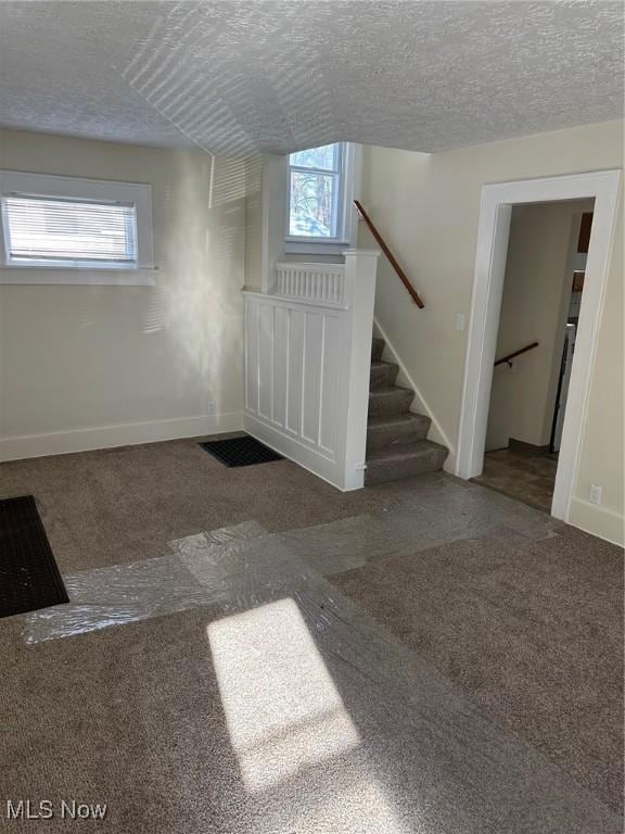 carpeted foyer entrance with a textured ceiling