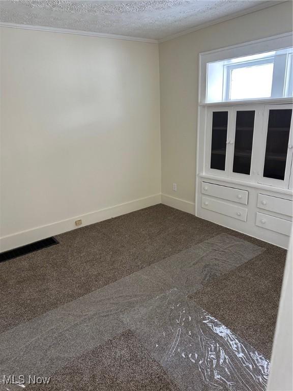 carpeted empty room featuring a textured ceiling and ornamental molding