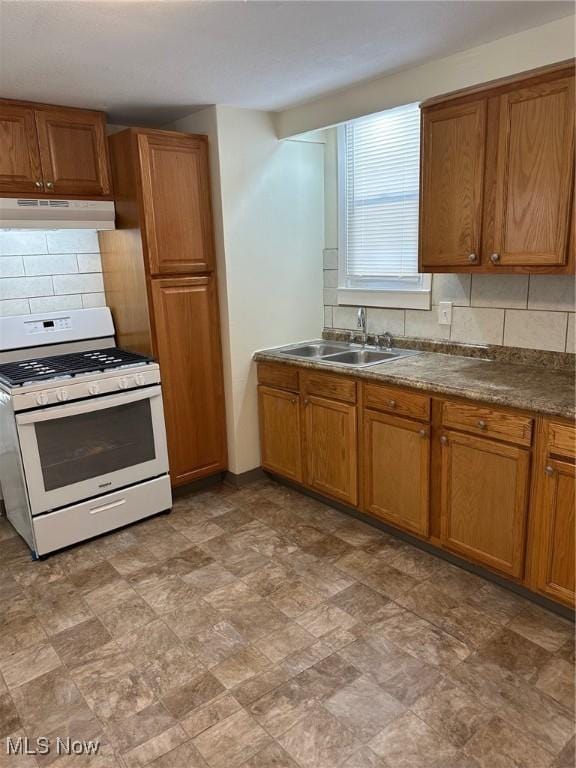 kitchen with white range with gas cooktop, decorative backsplash, and sink