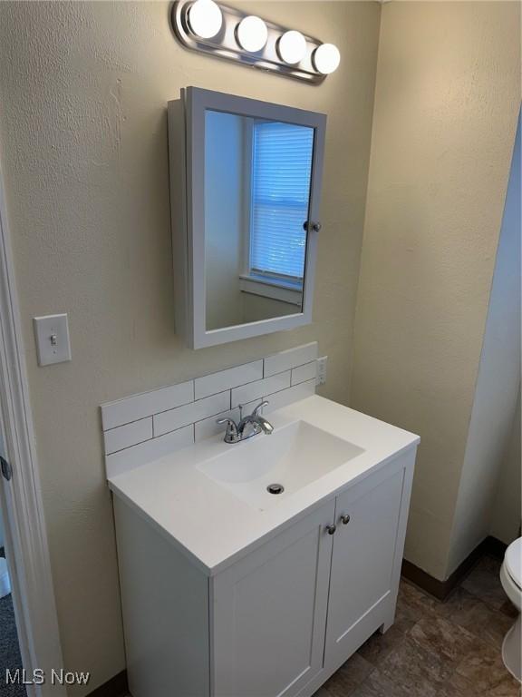 bathroom featuring decorative backsplash, vanity, and toilet