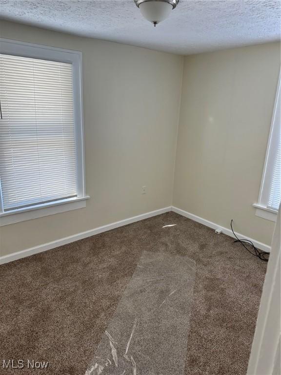 carpeted spare room featuring a textured ceiling