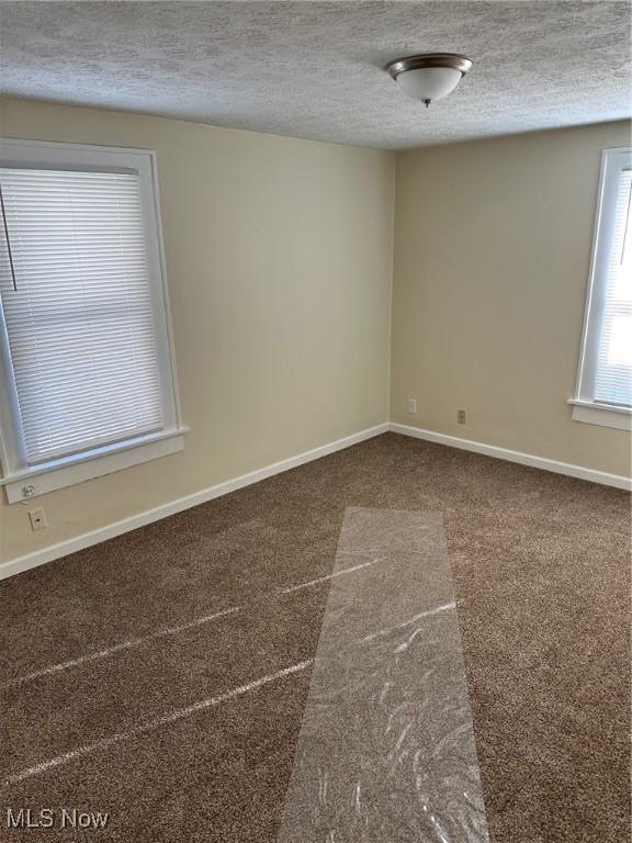 carpeted spare room featuring a textured ceiling