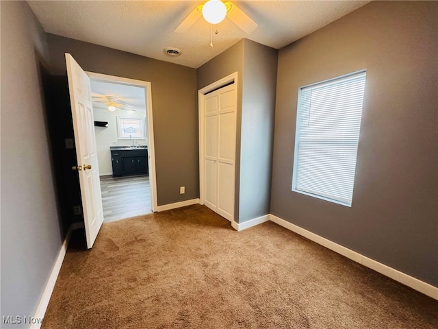 unfurnished bedroom with carpet floors, a closet, ceiling fan, and sink