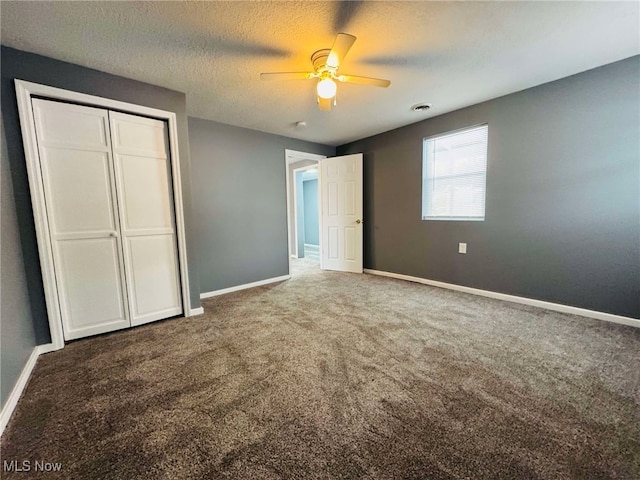 unfurnished bedroom with a textured ceiling, carpet floors, a closet, and ceiling fan