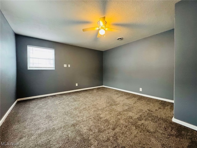 unfurnished room with ceiling fan, dark carpet, and a textured ceiling