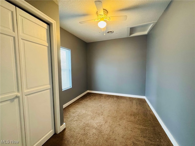 empty room featuring ceiling fan, dark carpet, and a textured ceiling