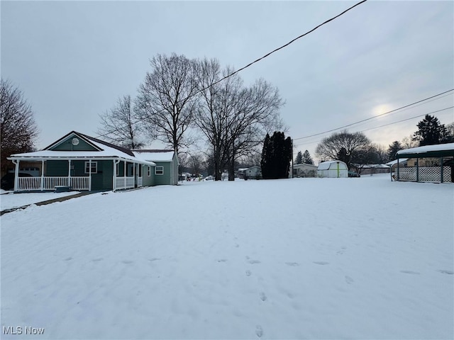 yard covered in snow featuring covered porch and a carport