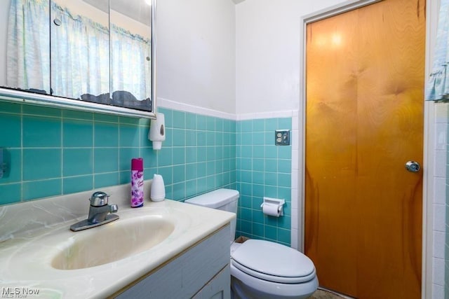 bathroom with vanity, tile walls, and toilet