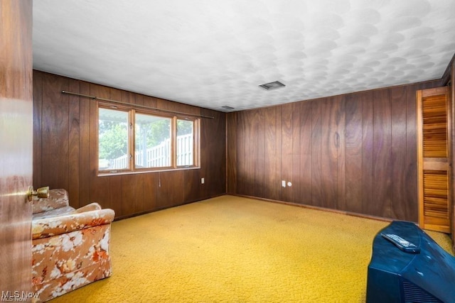 sitting room featuring light carpet and wooden walls