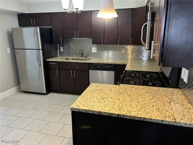 kitchen with decorative light fixtures, backsplash, stainless steel appliances, and sink