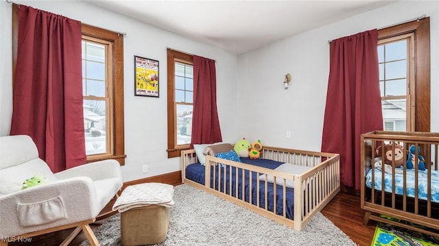 bedroom featuring wood-type flooring and a nursery area