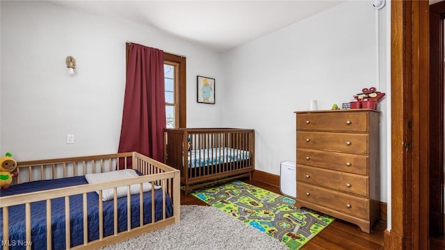 bedroom featuring hardwood / wood-style flooring and a nursery area