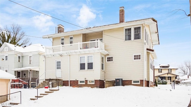 snow covered house featuring a balcony and central air condition unit