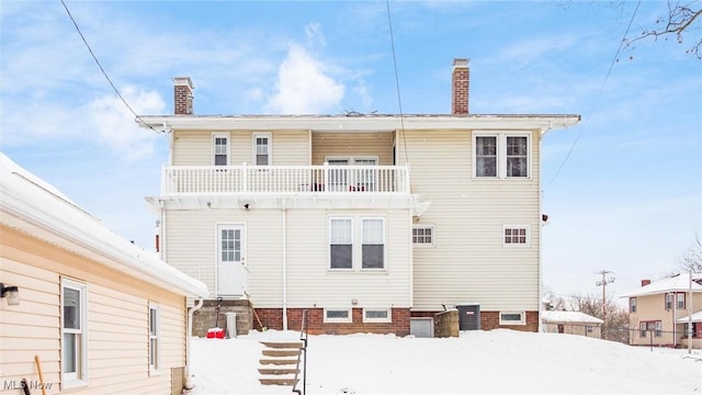 snow covered rear of property featuring a balcony