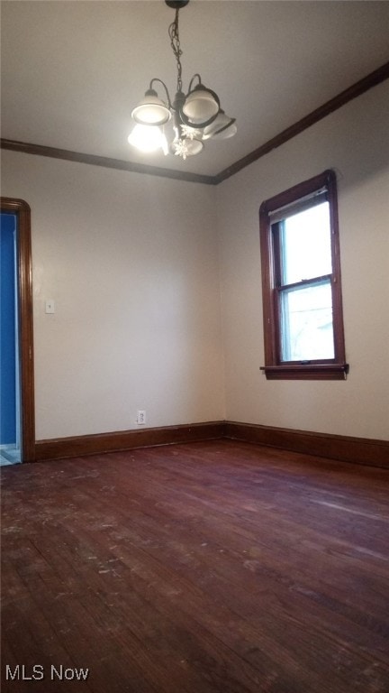 spare room with dark hardwood / wood-style flooring, an inviting chandelier, and ornamental molding