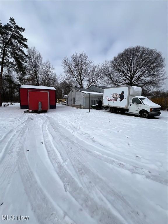 yard layered in snow with an outdoor structure