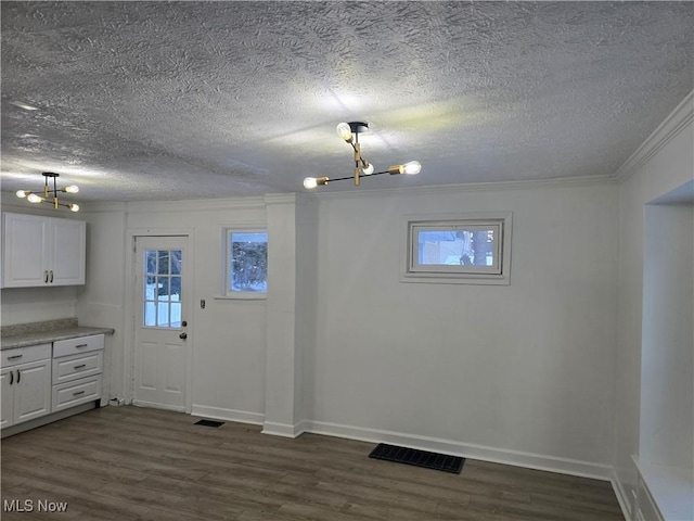 interior space with a textured ceiling, dark hardwood / wood-style floors, an inviting chandelier, and crown molding