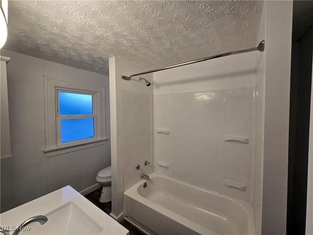 full bathroom with washtub / shower combination, a textured ceiling, toilet, and sink