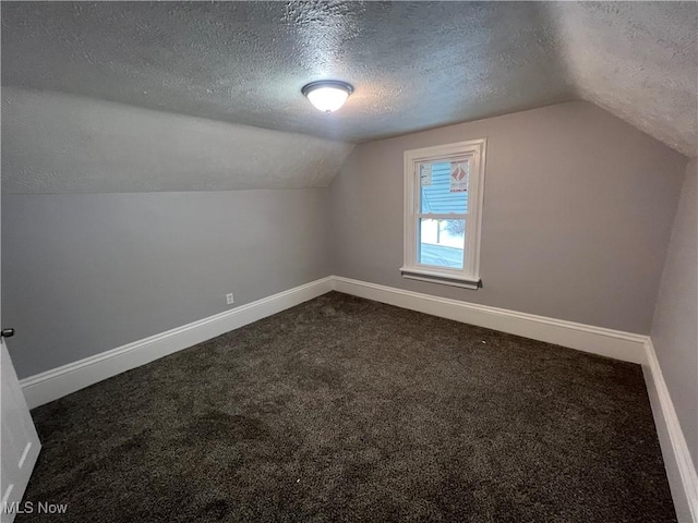 bonus room featuring a textured ceiling, baseboards, and dark colored carpet