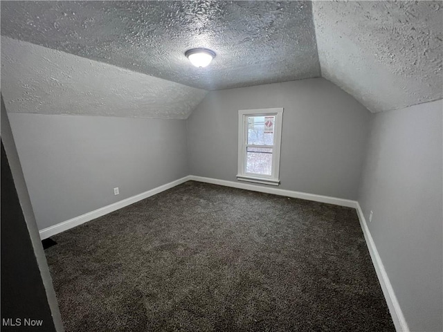 bonus room featuring baseboards, a textured ceiling, lofted ceiling, and dark carpet