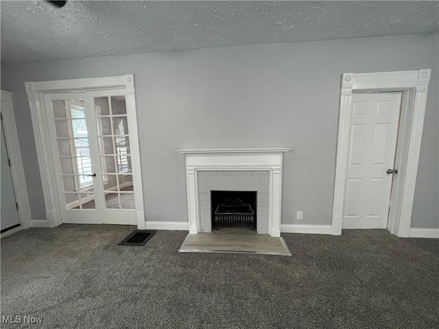 unfurnished living room with visible vents, carpet, a brick fireplace, and a textured ceiling