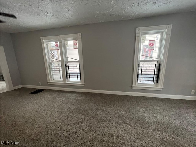 unfurnished room featuring visible vents, carpet, baseboards, and a textured ceiling