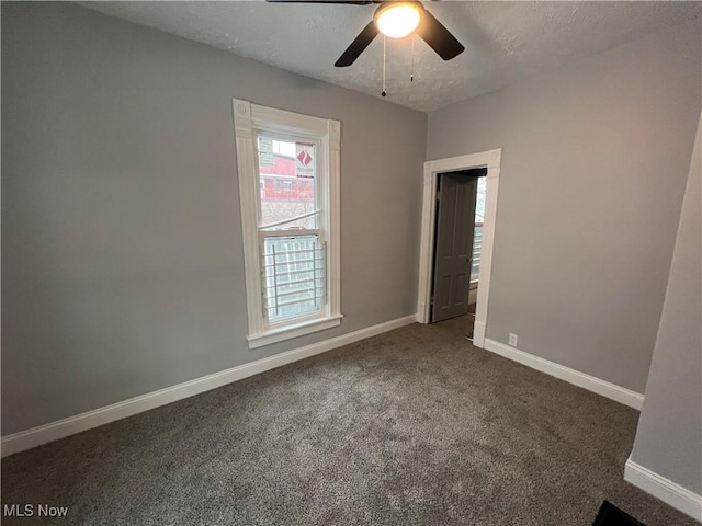 carpeted empty room with a textured ceiling, baseboards, and a ceiling fan