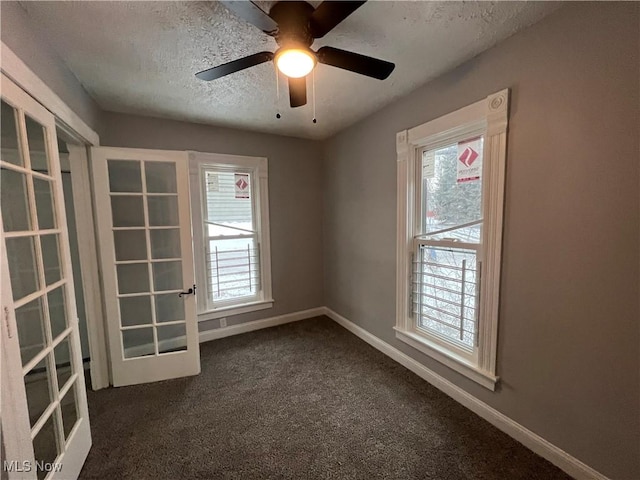 empty room with baseboards, dark colored carpet, french doors, and a textured ceiling