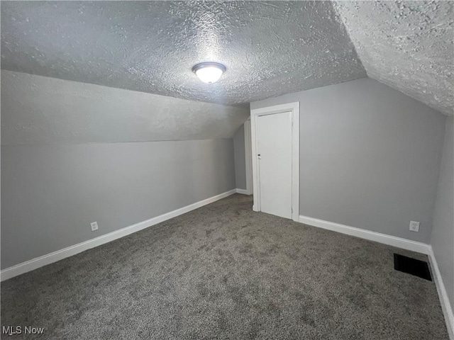 additional living space with carpet flooring, baseboards, visible vents, and a textured ceiling