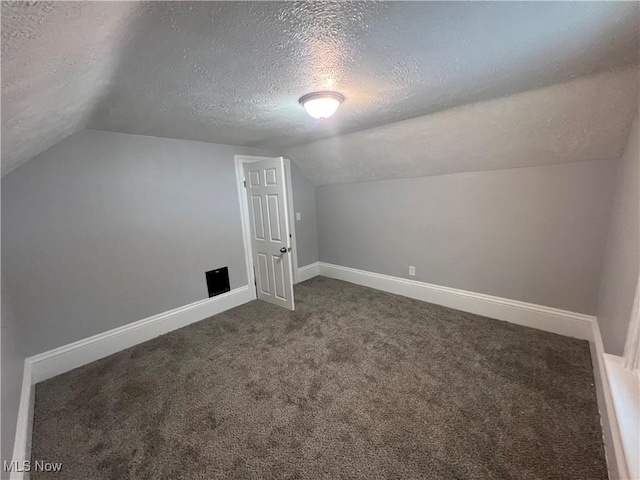 additional living space featuring carpet flooring, a textured ceiling, baseboards, and vaulted ceiling