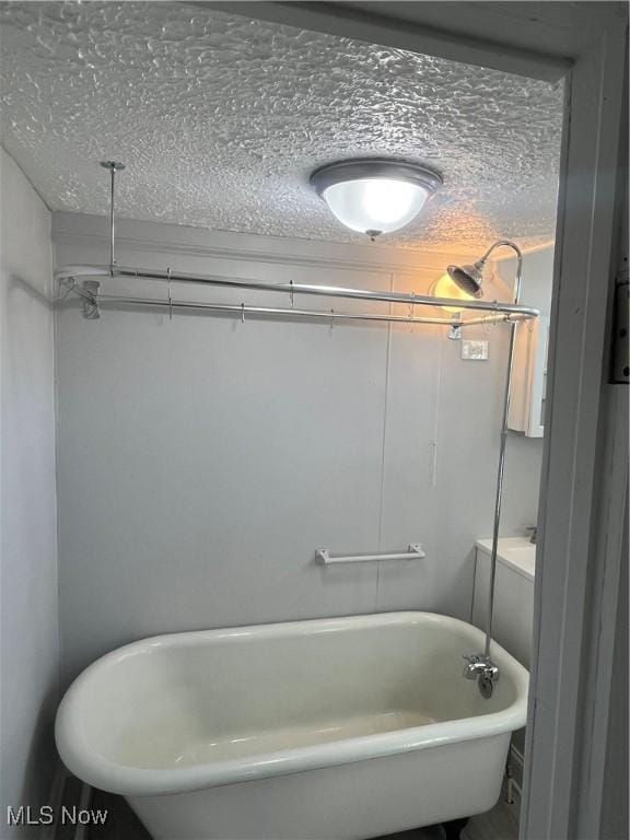 full bathroom with a textured ceiling and a freestanding bath