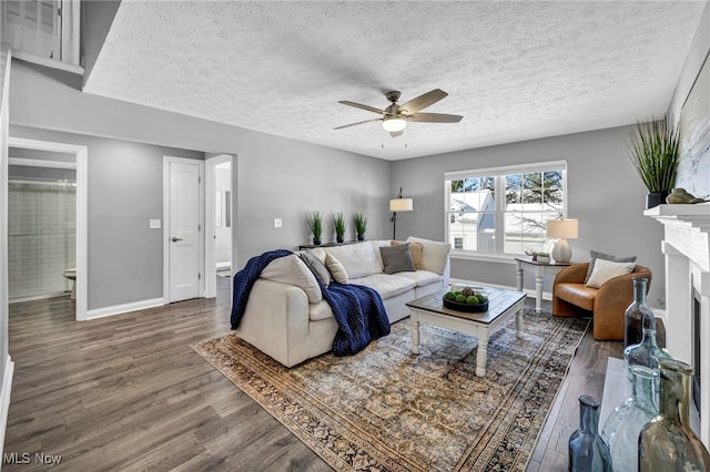 living room with hardwood / wood-style floors, ceiling fan, a fireplace, and a textured ceiling