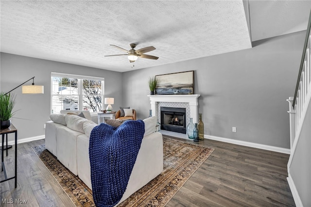 living room with a textured ceiling, dark hardwood / wood-style flooring, and ceiling fan