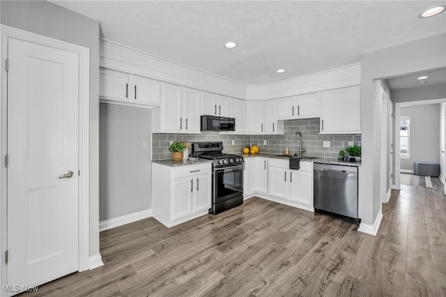 kitchen featuring appliances with stainless steel finishes, light wood-type flooring, light stone counters, sink, and white cabinets