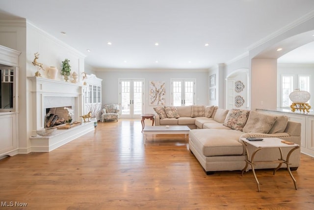 living room featuring a fireplace, french doors, light hardwood / wood-style floors, and crown molding