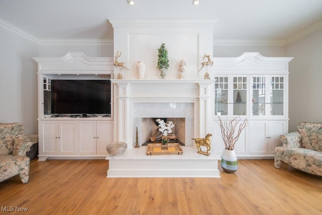 living room with a premium fireplace, crown molding, and light hardwood / wood-style floors