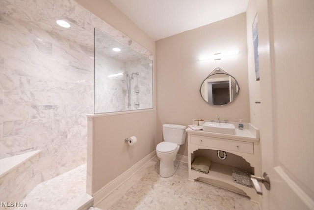 bathroom featuring a tile shower, vanity, and toilet