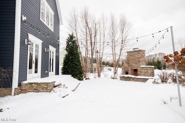 yard covered in snow featuring an outdoor stone fireplace