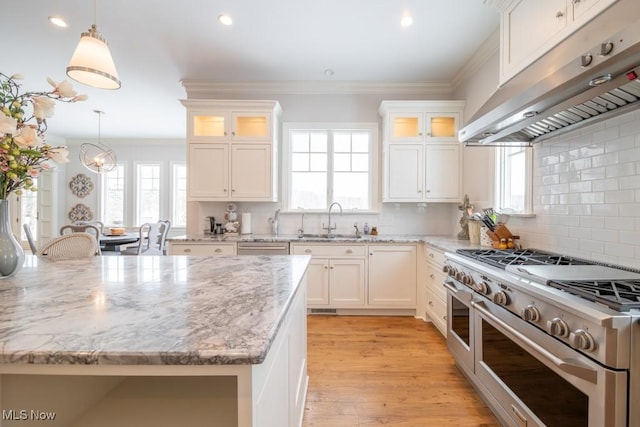 kitchen featuring white cabinetry, sink, hanging light fixtures, and range with two ovens